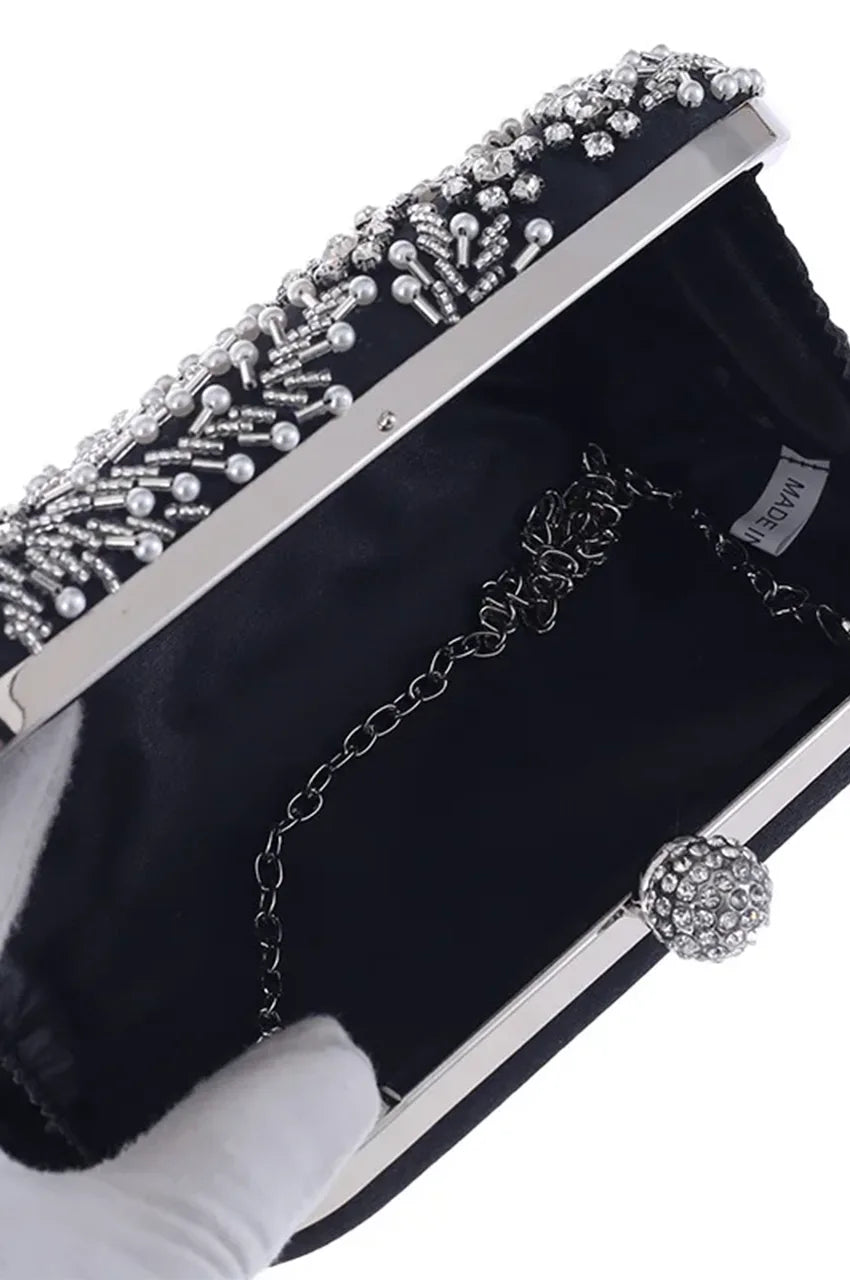 Interior view of open black satin clutch revealing black lining, gusseted sides, and a detachable silver chain strap.