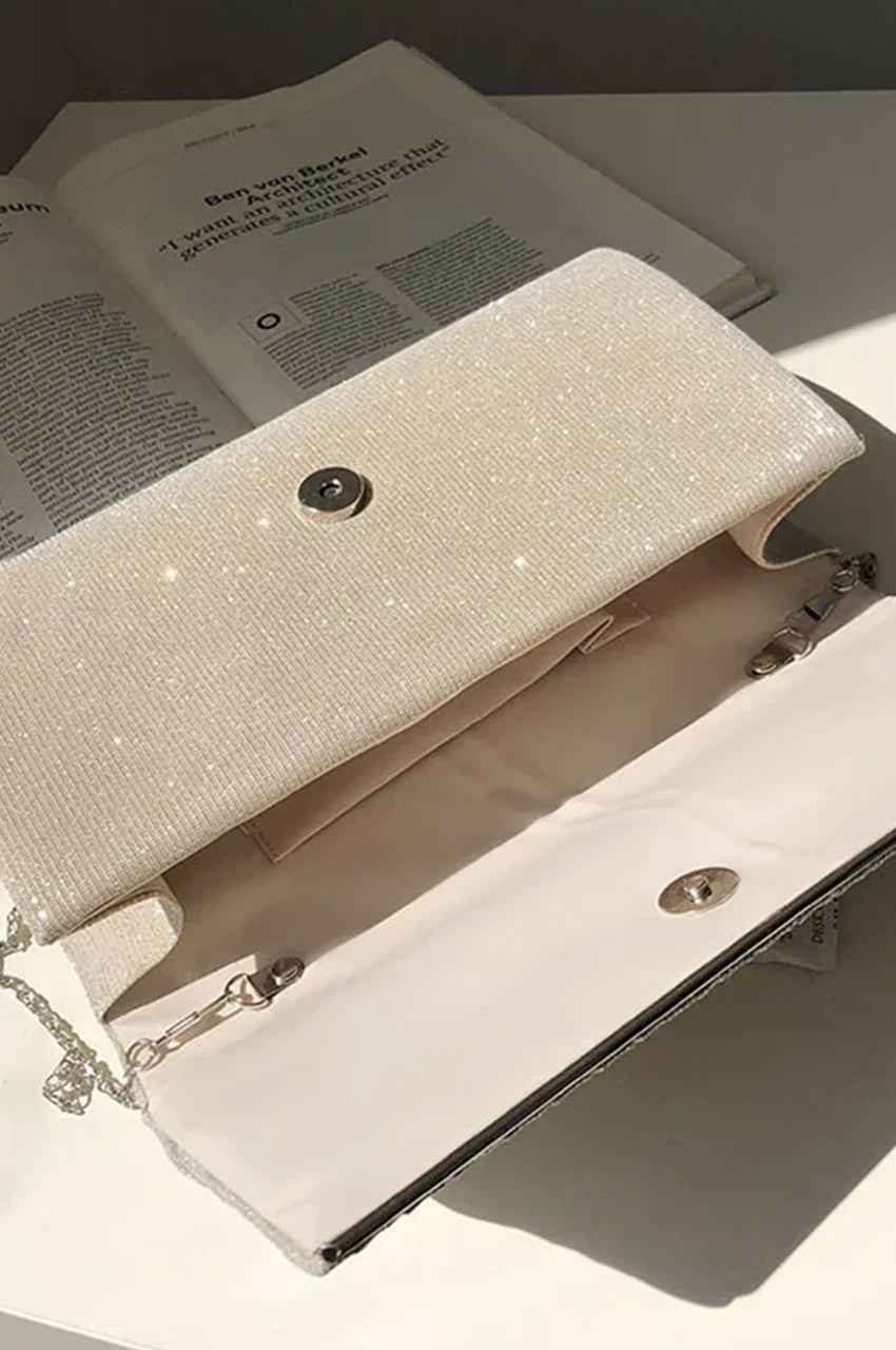 Interior view of the open champagne gold evening bag revealing the beige lining, internal slip pocket, and silver hardware attachments.