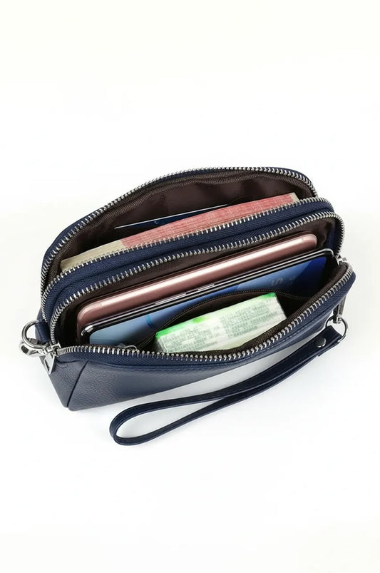 Top view inside open navy blue leather clutch showing organized compartments for smartphone and cash.