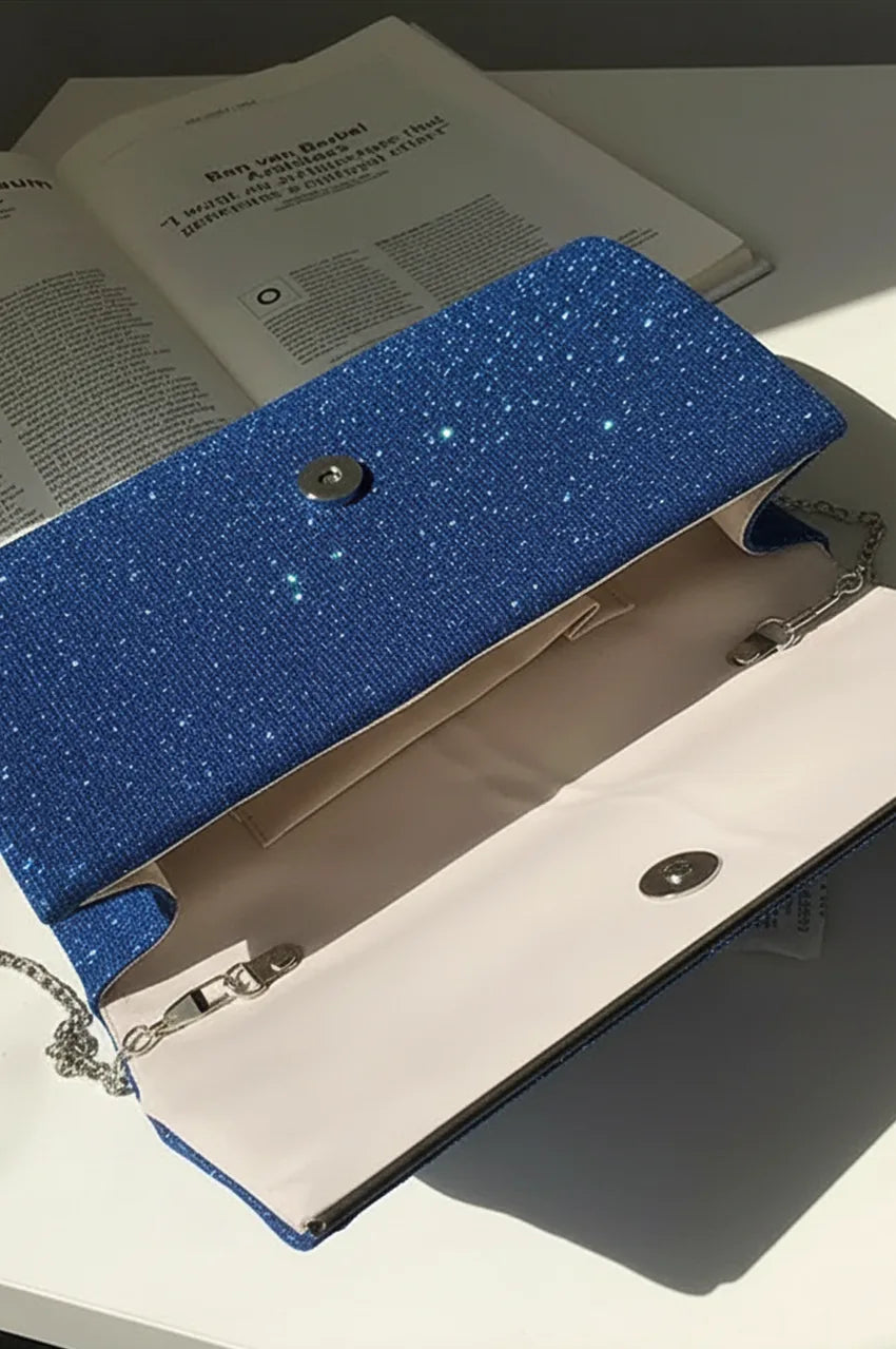 Interior view of open night blue clutch bag displaying beige lining, internal pocket, and chain attachments.