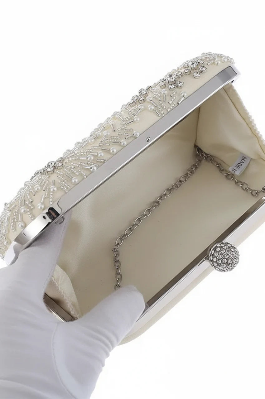 Interior view of open white bridal clutch revealing cream fabric lining, side gussets, and detachable silver link chain.