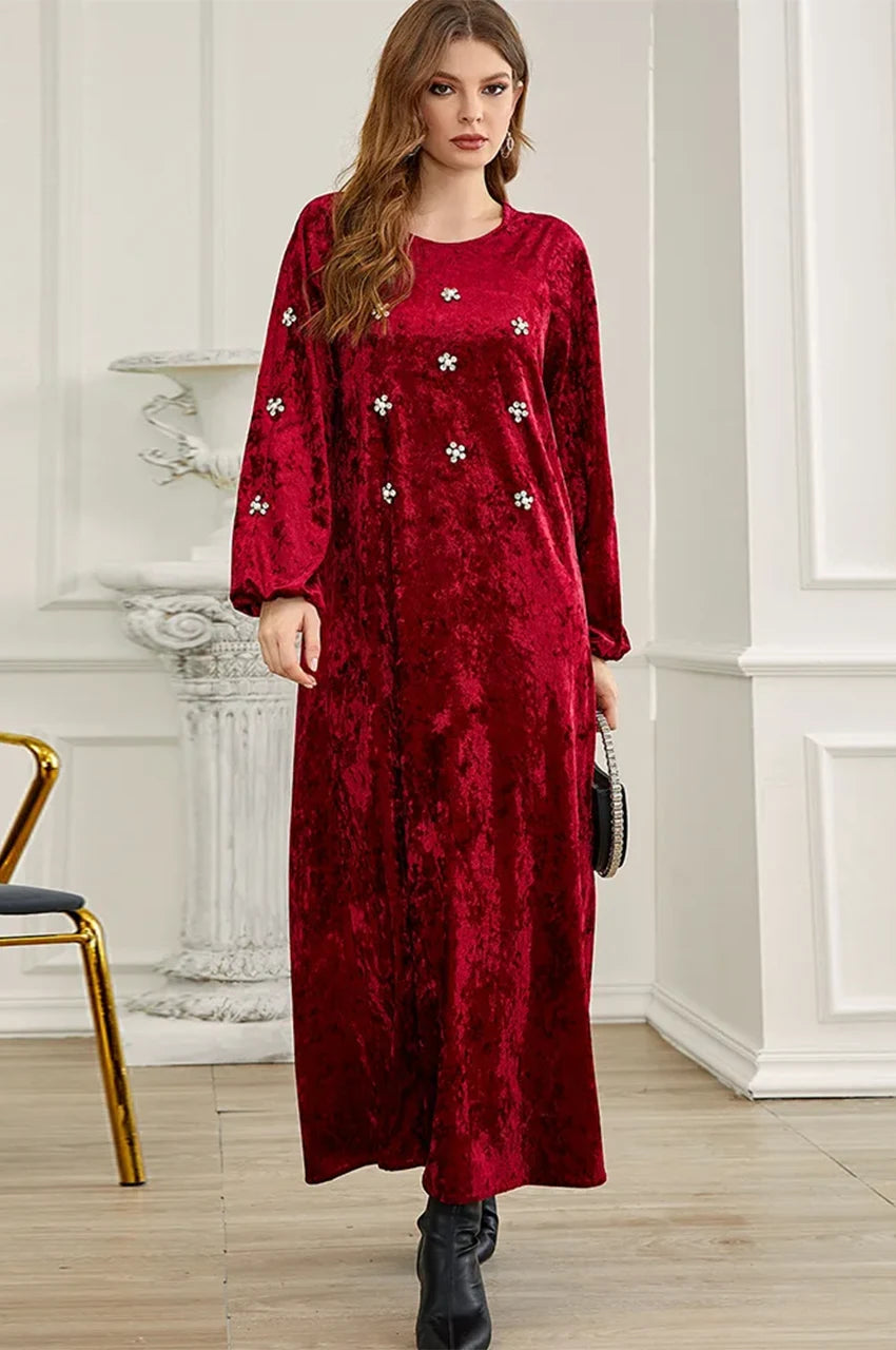 Woman wearing luxury Oriya ruby kaftan dress standing in a white room.