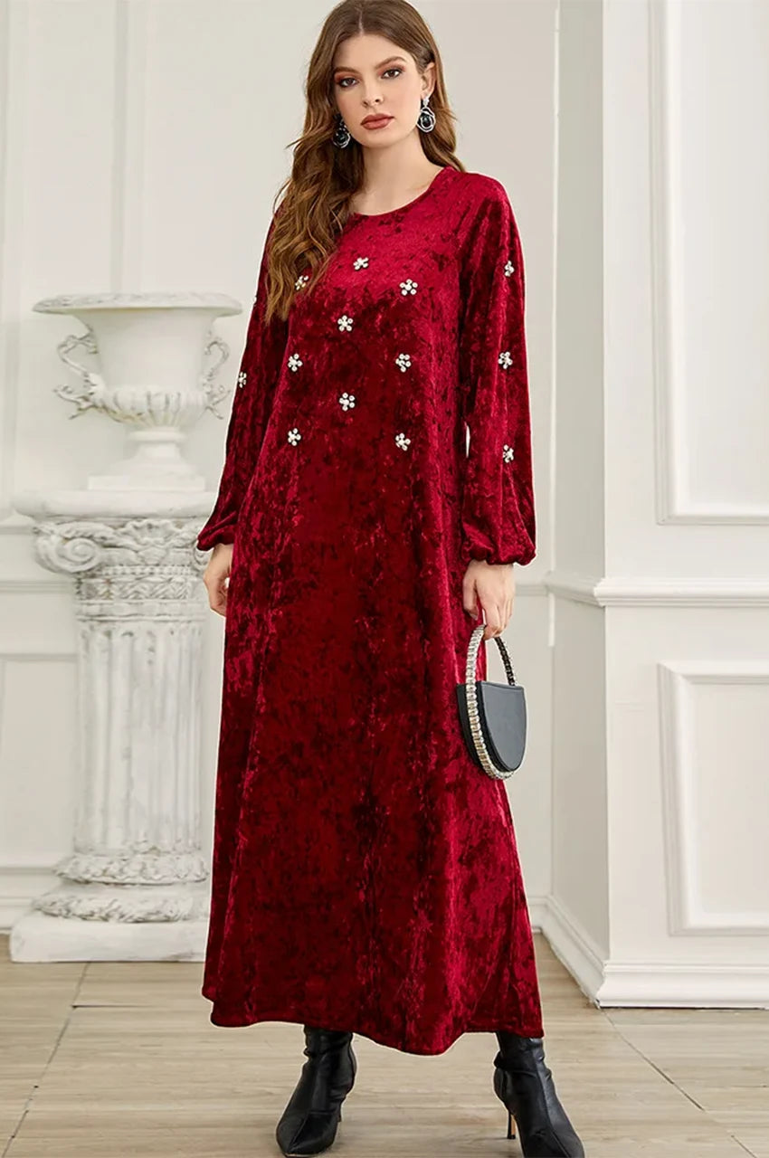 Front angle of velvet ruby kaftan dress showing fabric drape and floral embellishments.