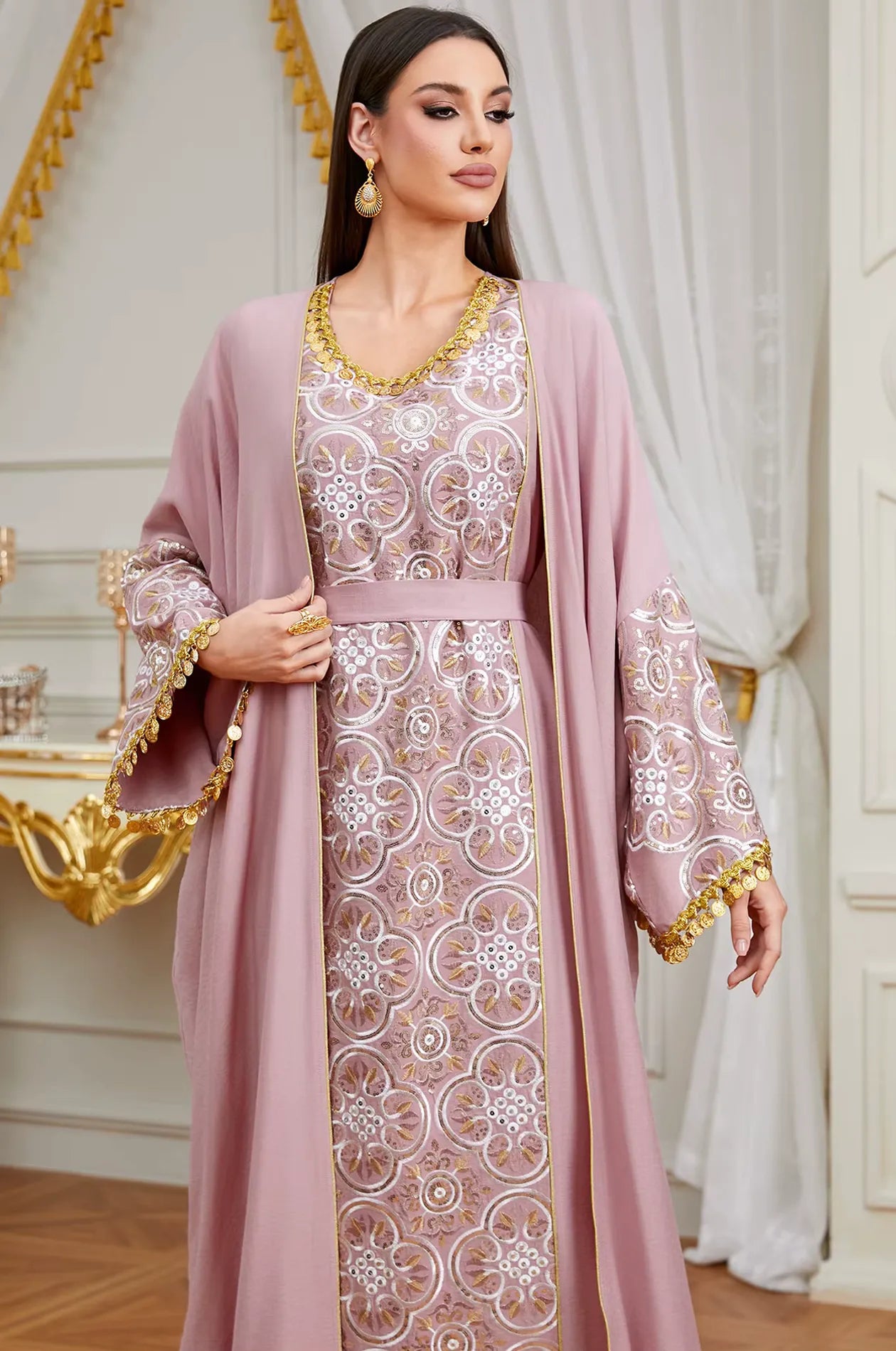 Close-up of the silver embroidery, matching belt, and gold coin tassels on the sleeves of the pink Novae kaftan.