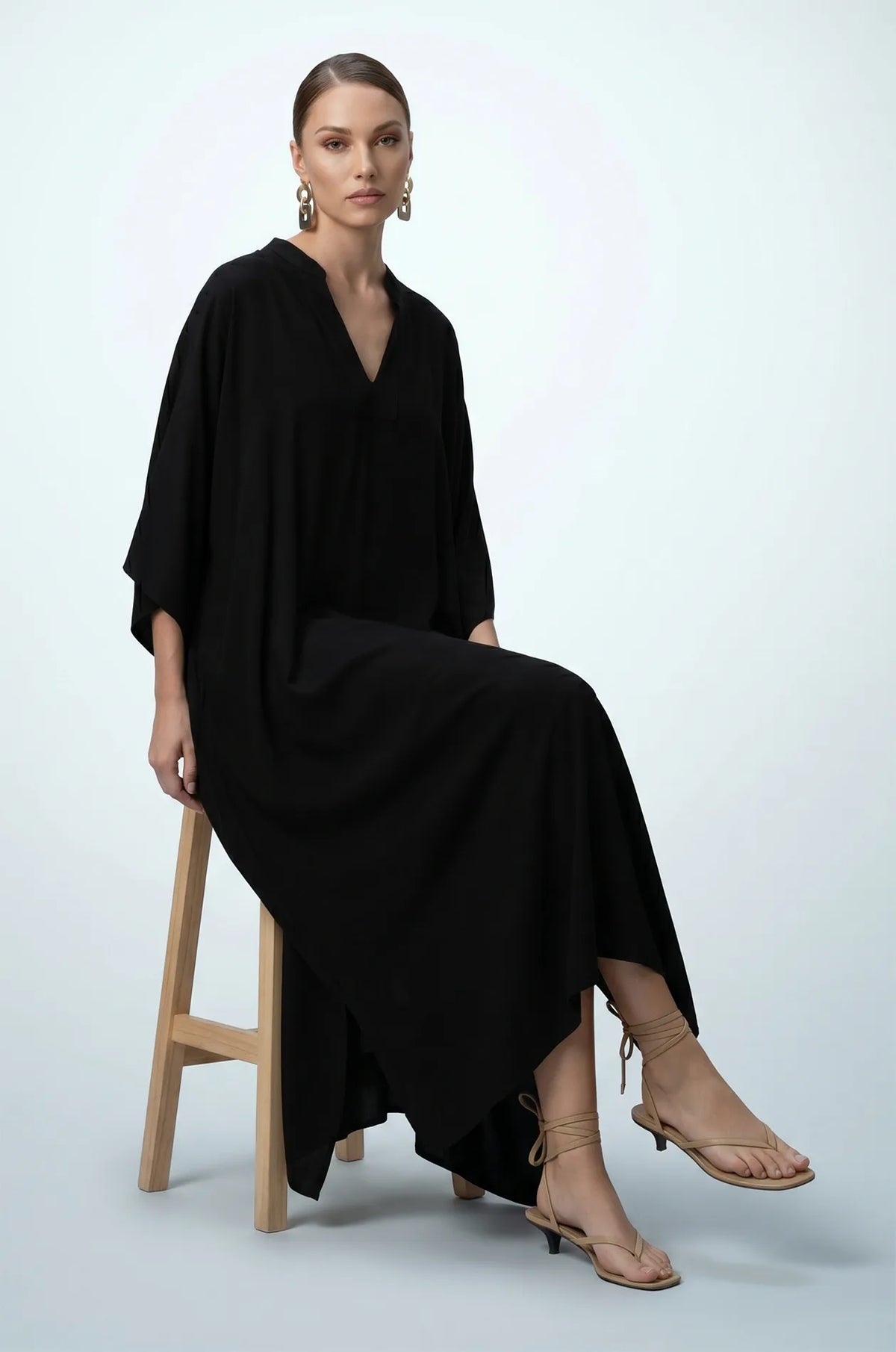 Woman seated wearing black minimalist plain kaftan