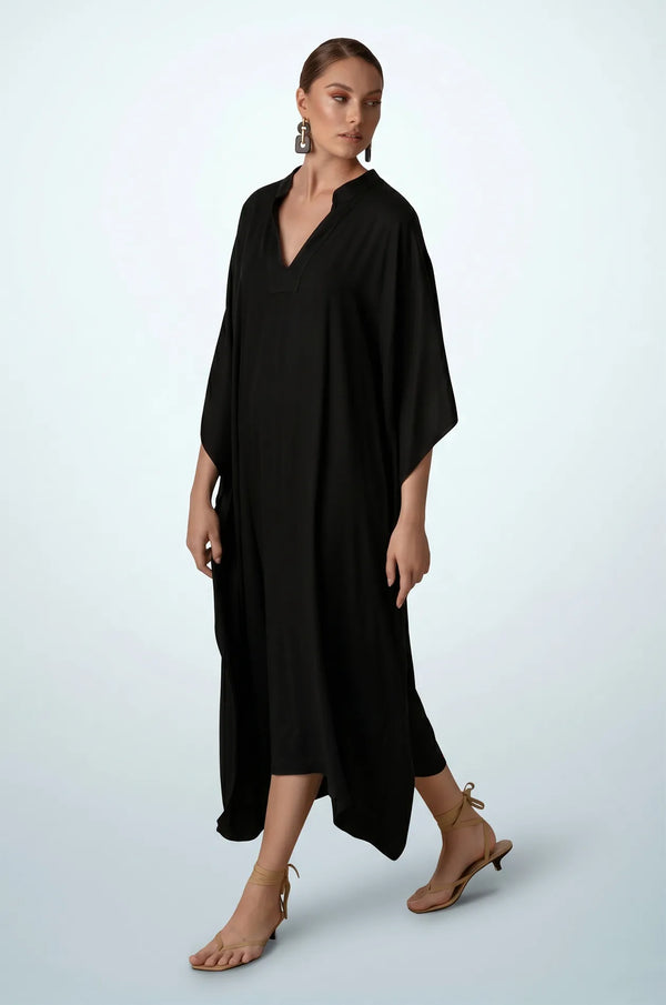 Woman walking in black plain kaftan with handkerchief hem