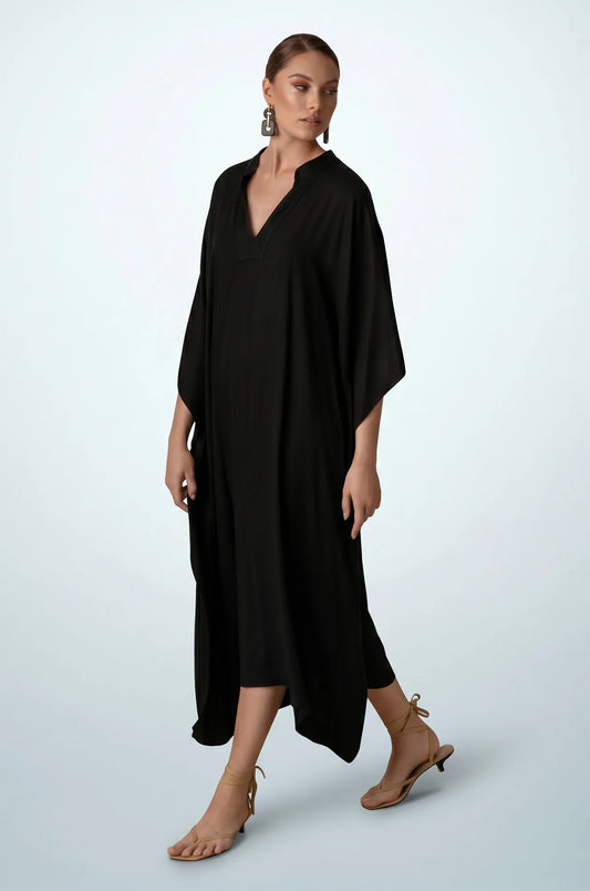 Woman walking in black plain kaftan with handkerchief hem