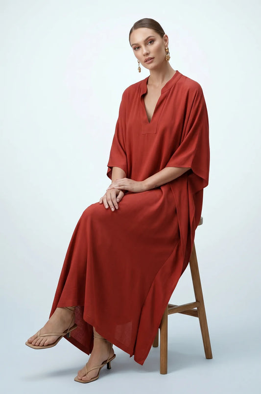 Woman seated wearing terracotta orange minimalist plain kaftan