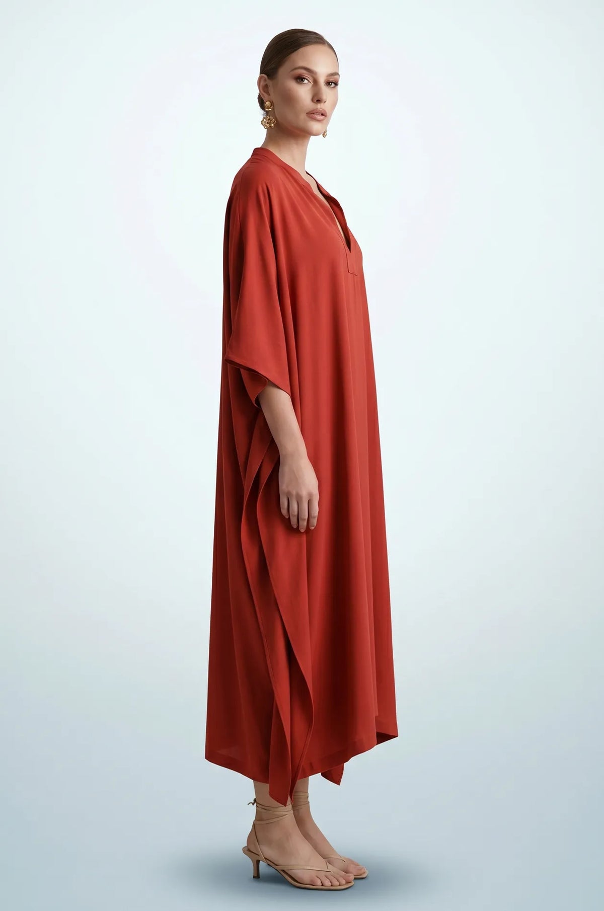 Side profile of terracotta orange plain kaftan showing flowing drape