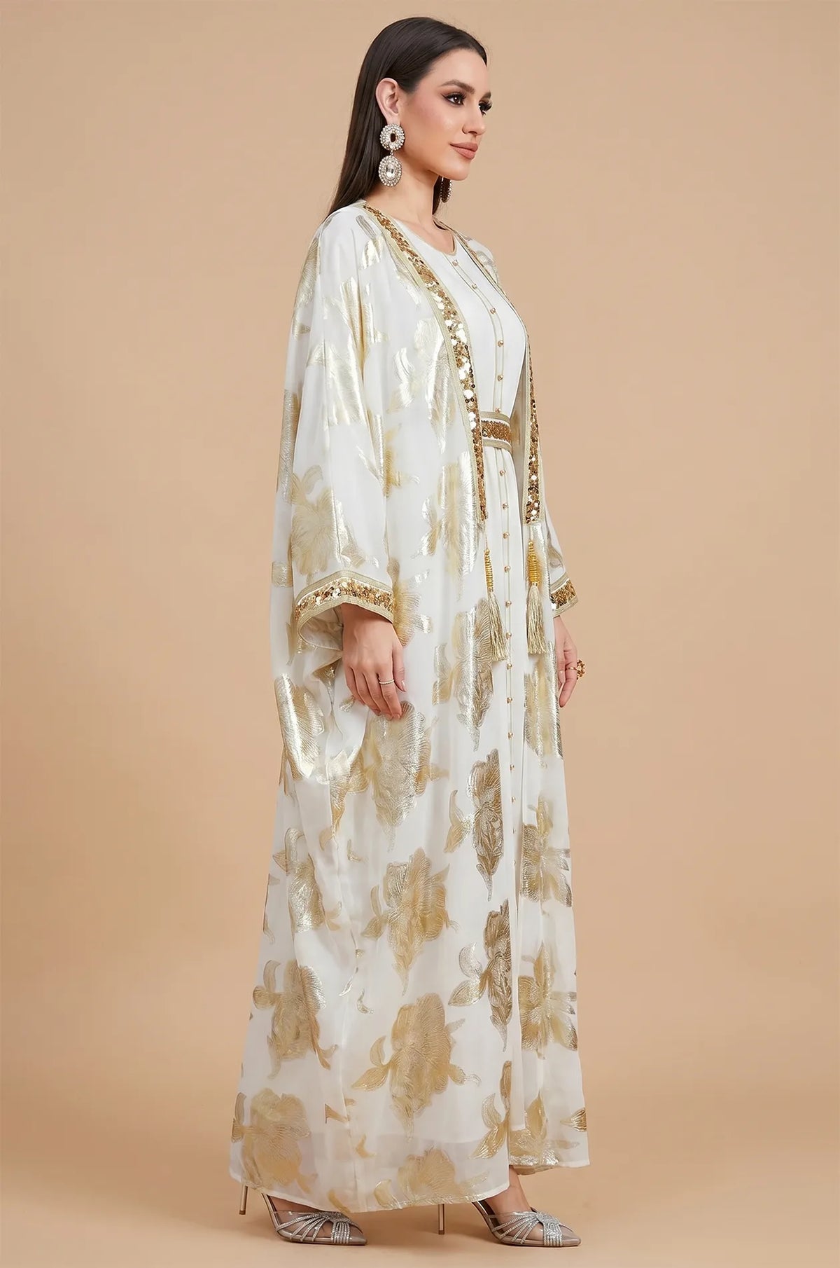 Side profile of a model wearing the white and gold Puppis luxe kaftan highlighting the flowing butterfly sleeve design.
