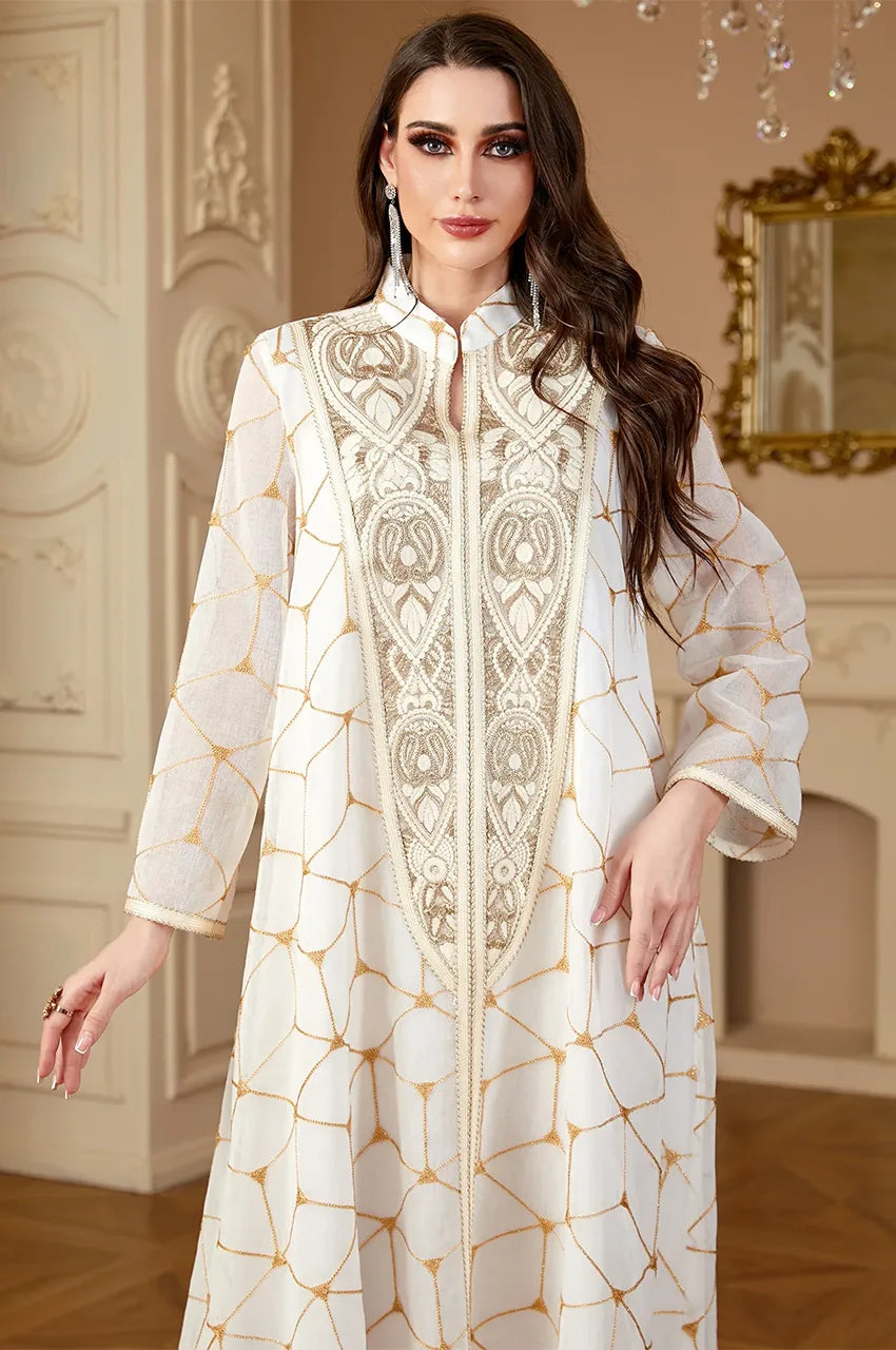 Close up of high-neck white kaftan with intricate gold chest embroidery.