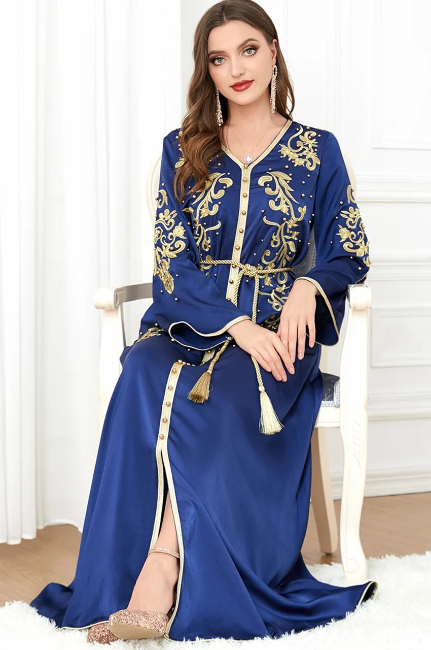 Woman seated wearing blue and gold Rayah kaftan with tassel belt