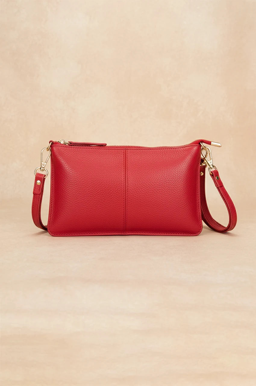 Front view of the vibrant red leather crossbody bag with adjustable strap and silver hardware.