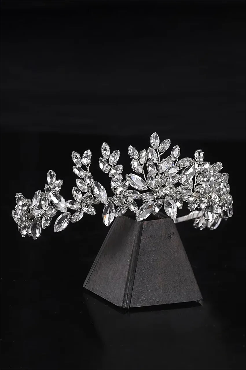 Side angle of sparkling rhinestone crown showing intricate leaf motif and silver setting.