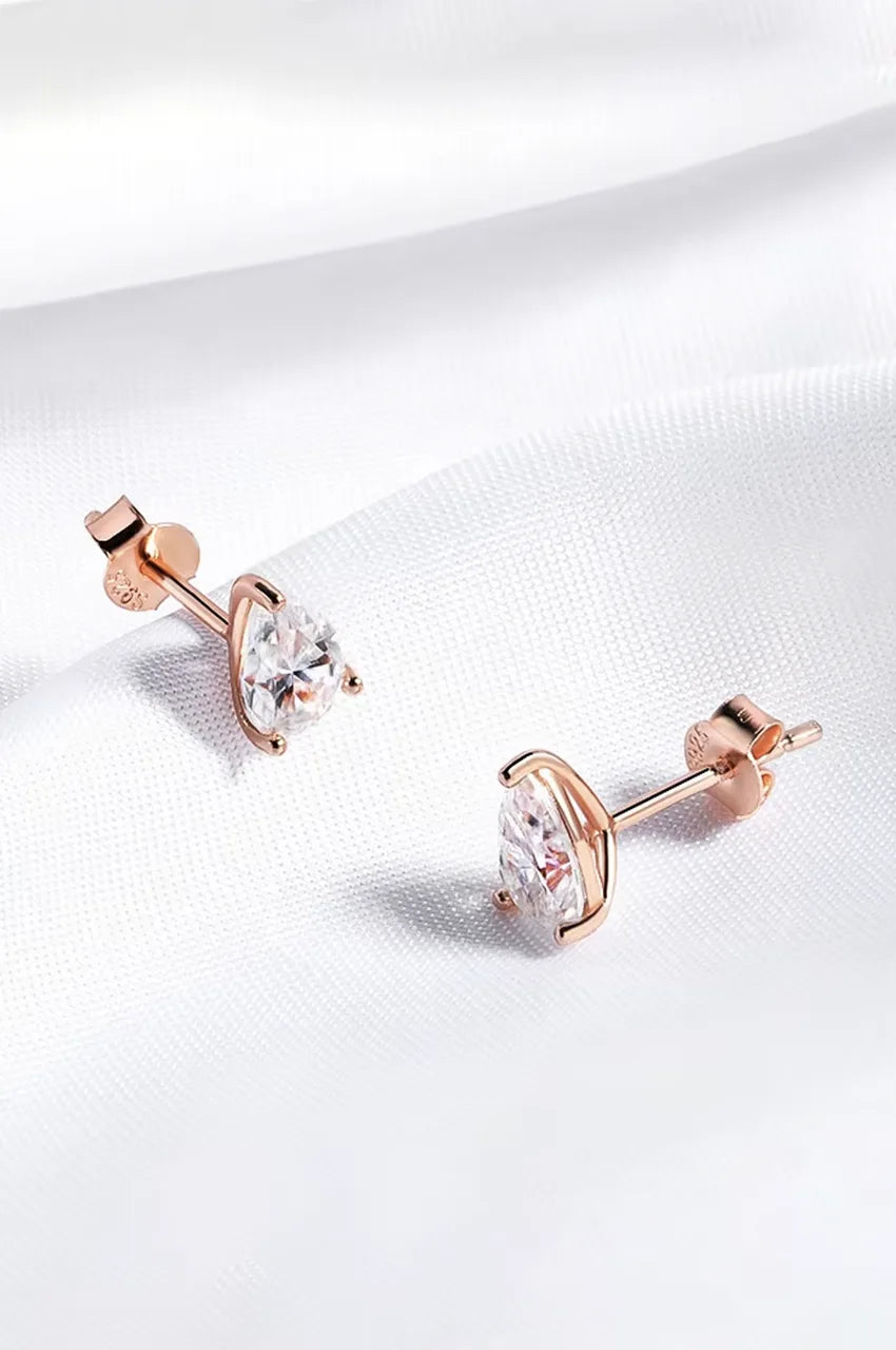 Pair of rose gold pear-shaped cubic zirconia studs on white silk.