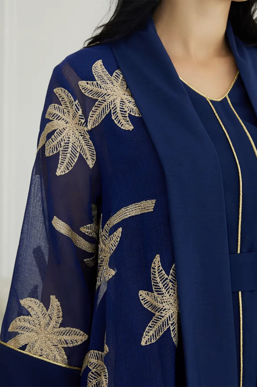 Close-up of the shimmering gold palm tree kaftan embroidery on deep navy organza fabric.