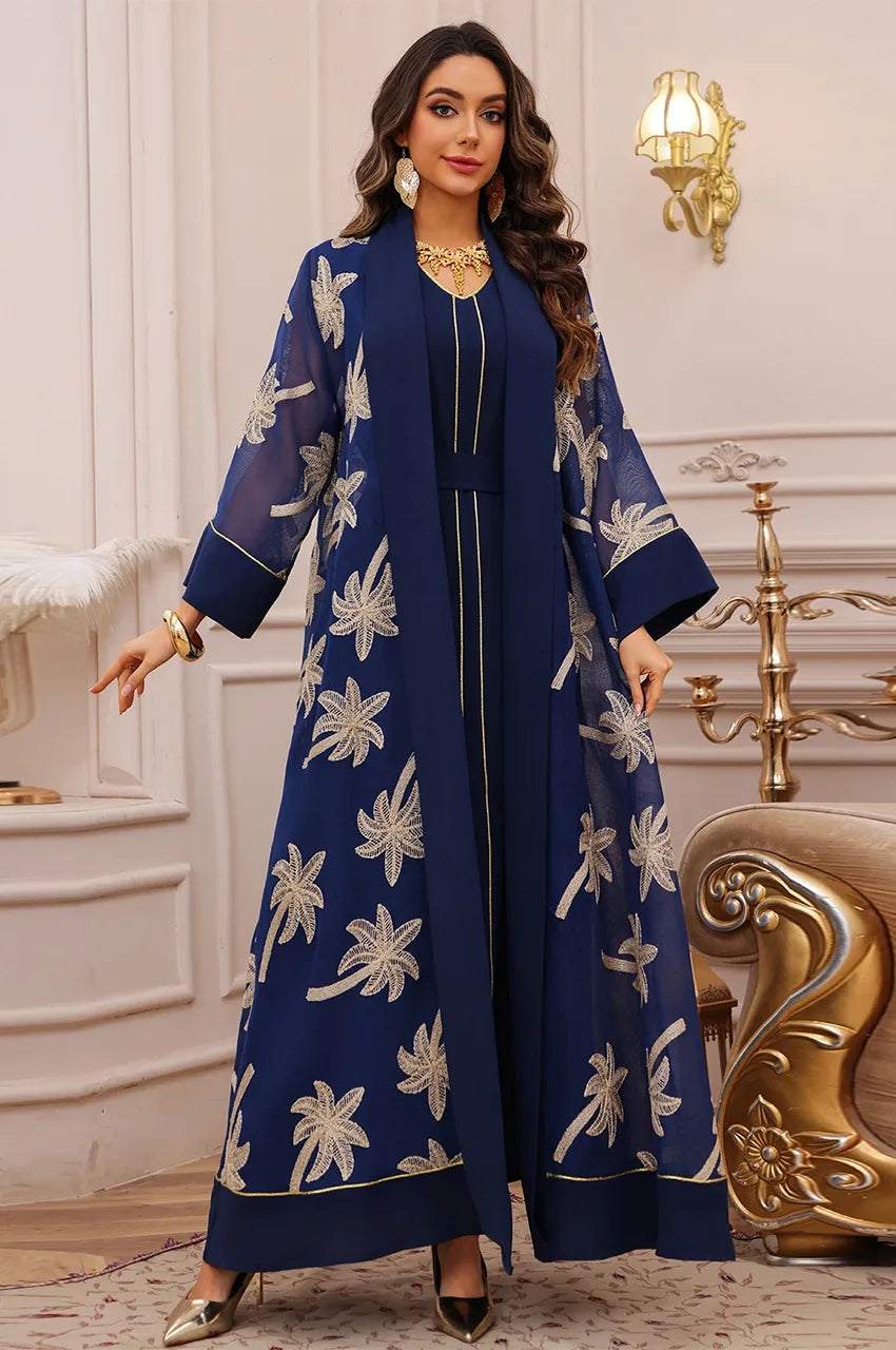 Lifestyle pose of the dark blue palm tree kaftan in a luxury resort setting with gold accessories.