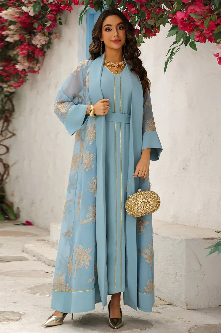 Lifestyle shot of the light blue palm tree kaftan in a tranquil summer setting, emphasizing the sun-drenched aesthetic.