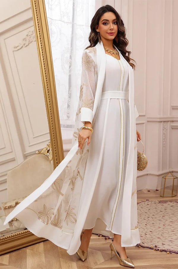 Lifestyle shot of the white palm tree kaftan in a luxury resort setting, emphasizing the sun-drenched aesthetic.