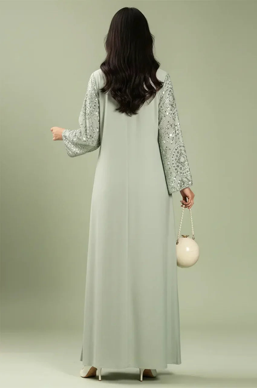 Back view of the Maeli Kaftan in sage green showing the smooth fabric and embroidered sleeve detail.