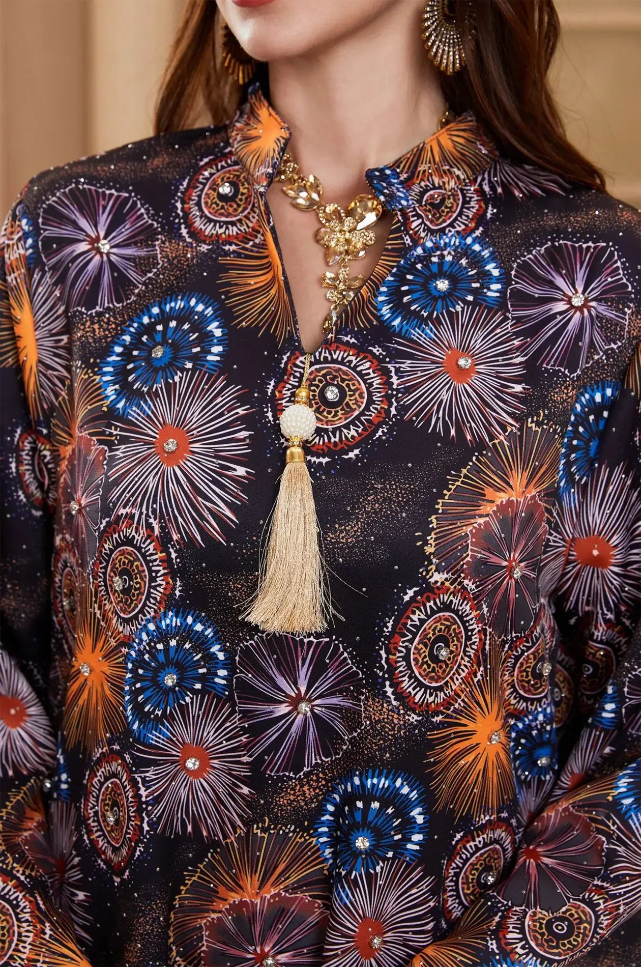Close-up of the Samia celestial kaftan neck detail showing gold tassel, pearl bead, and sparkling rhinestones.