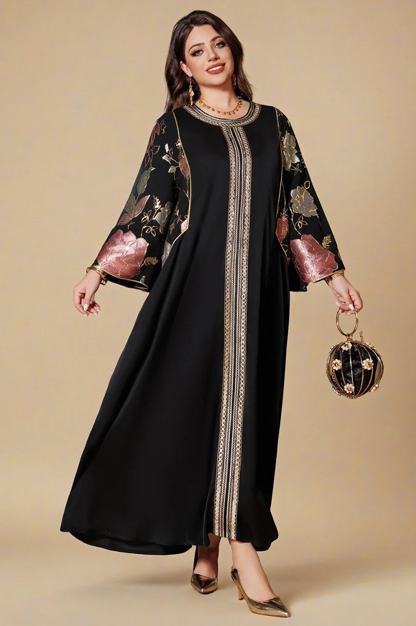 Elegant woman wearing Samira Black Pakistan Kaftan holding gold clutch, floral jacquard sleeves and gold front details.