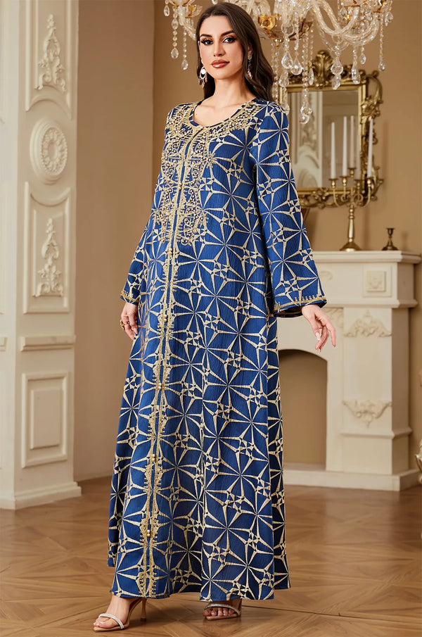 Three-quarter view of the Selas Blue textured kaftan dress in a luxury interior with a chandelier and fireplace.