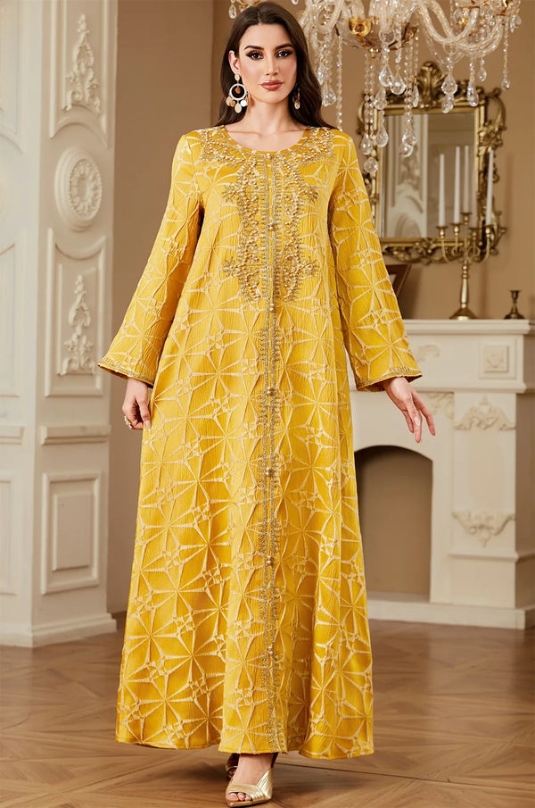 Full front shot of the Selas Yellow textured kaftan dress standing in a luxury room with a chandelier.