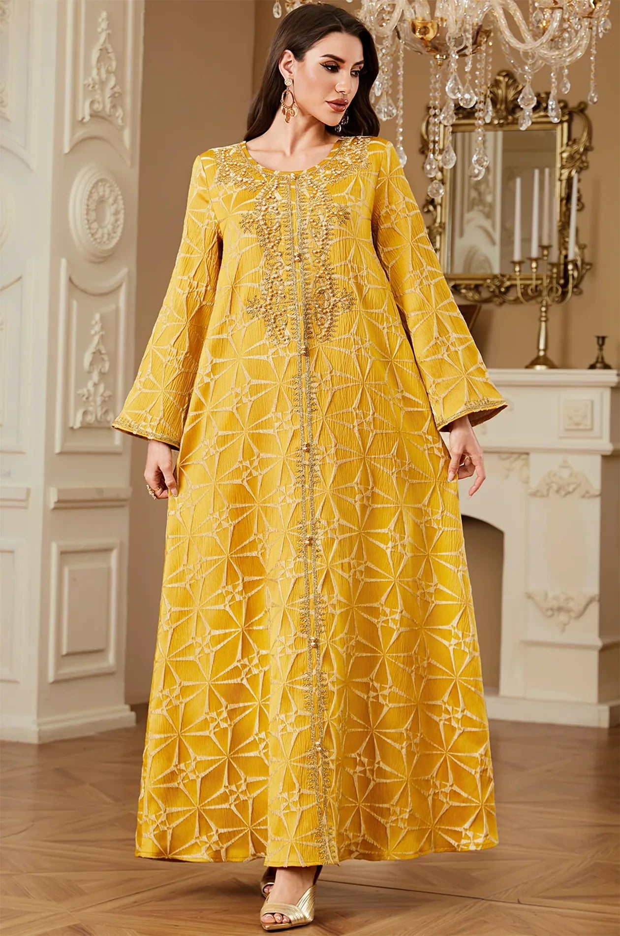 Model posing in the Selas Yellow textured kaftan dress in an ornate setting with a white fireplace.