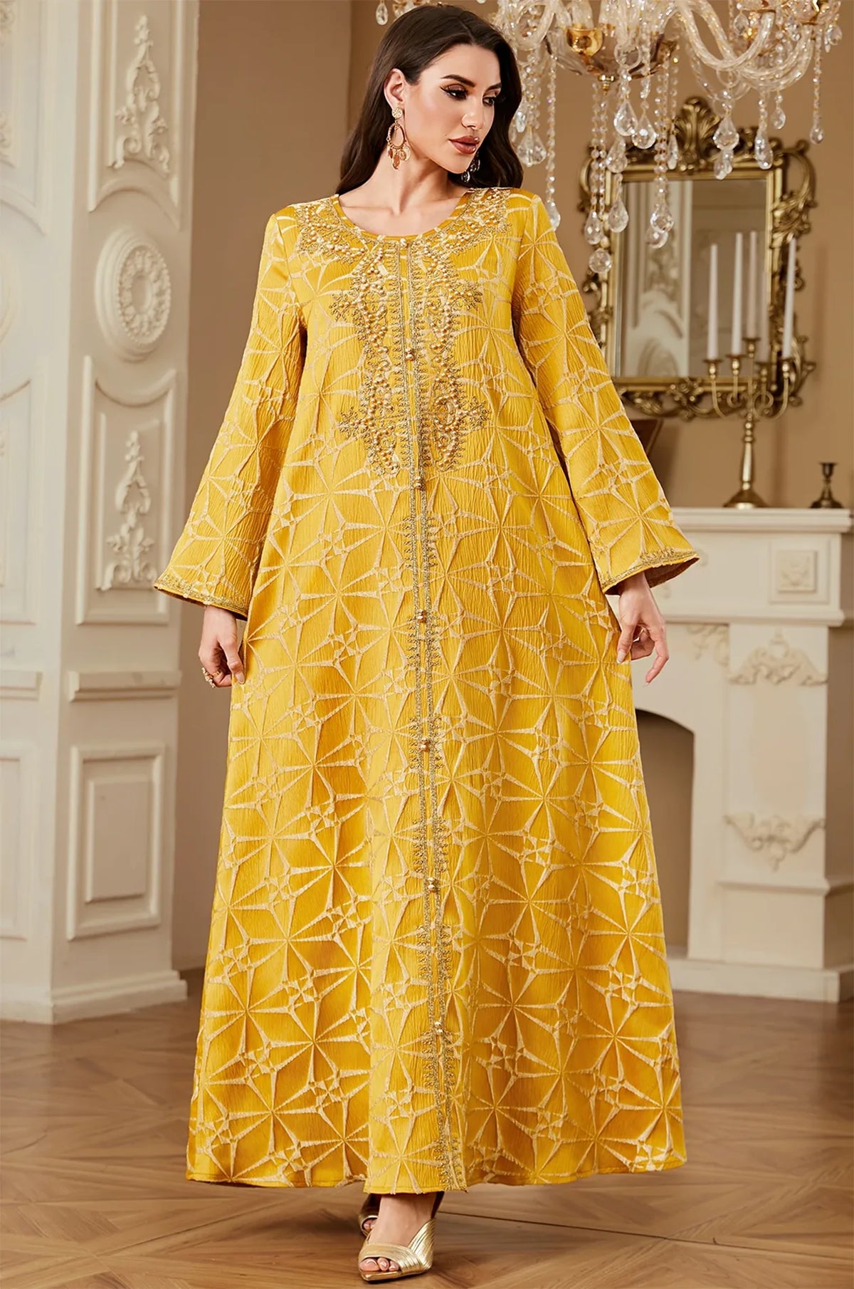 Model posing in the Selas Yellow textured kaftan dress in an ornate setting with a white fireplace.