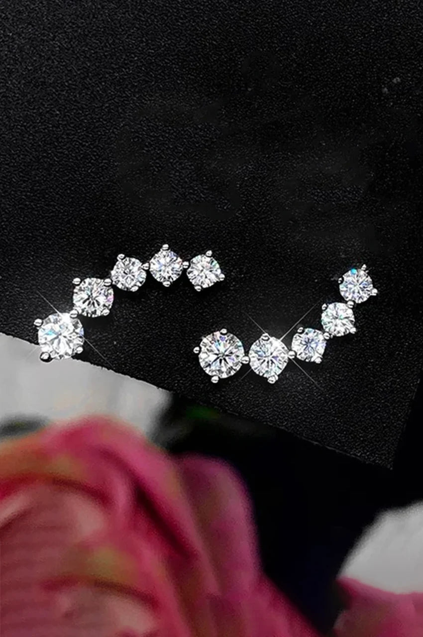 High contrast photo of moissanite ear climbers sparkling against a dark textured background.