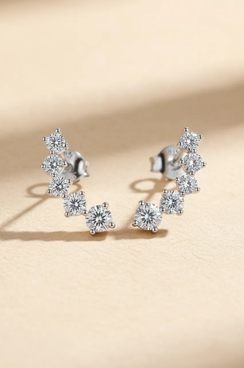 Front view of silver ear climber earrings with 7 graduated cubic moissanite stones on beige background.