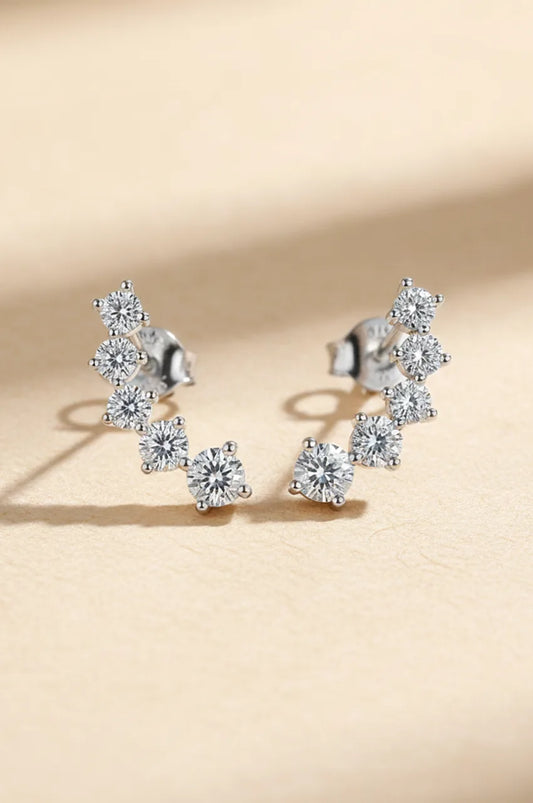 Front view of silver ear climber earrings with 7 graduated cubic moissanite stones on beige background.