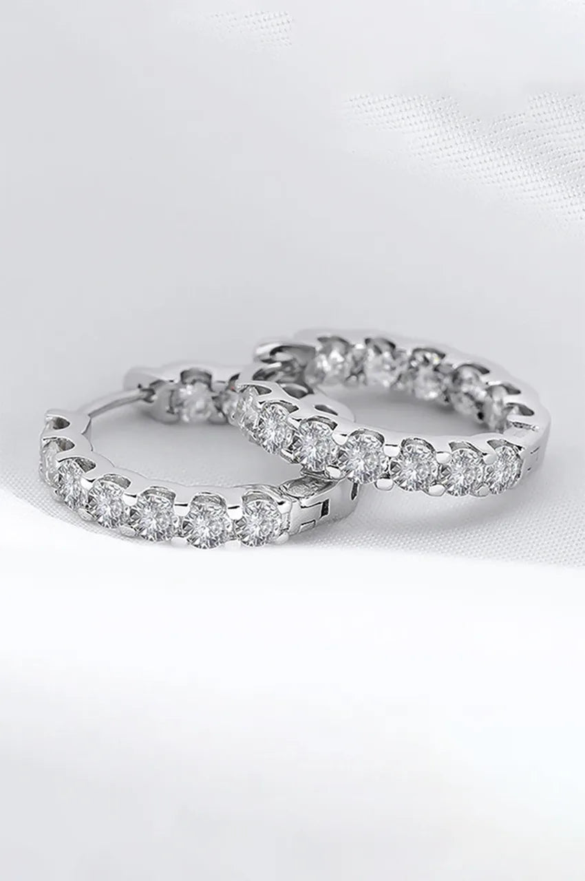 Detailed macro shot of silver hoop earrings showing the hinge closure and stone brilliance.