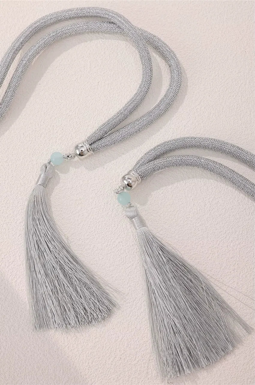 Detail of silver belt tassels featuring a unique light blue bead accent at the cap.