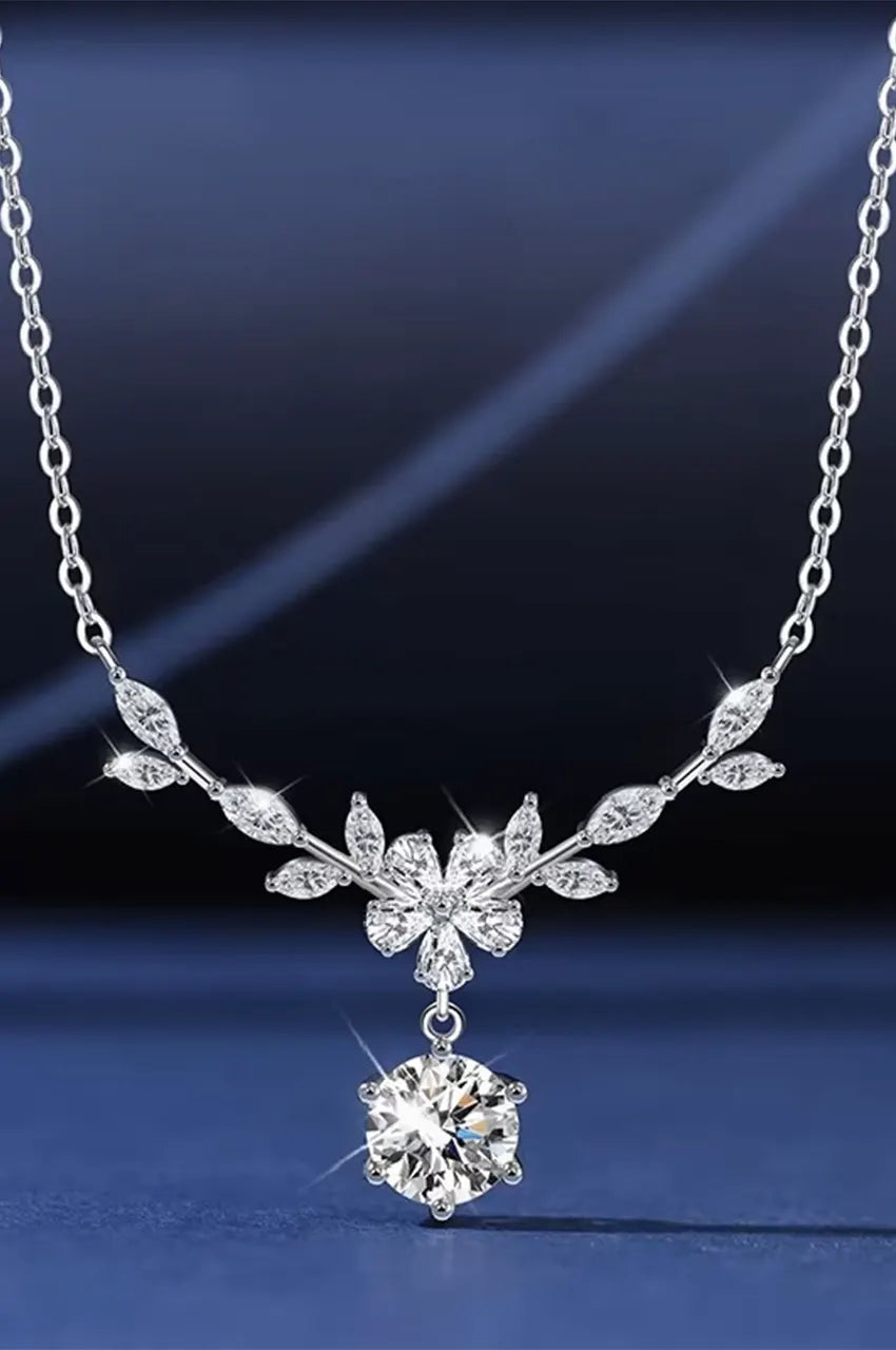 Full view of silver Y-necklace with crystal flower center on blue background