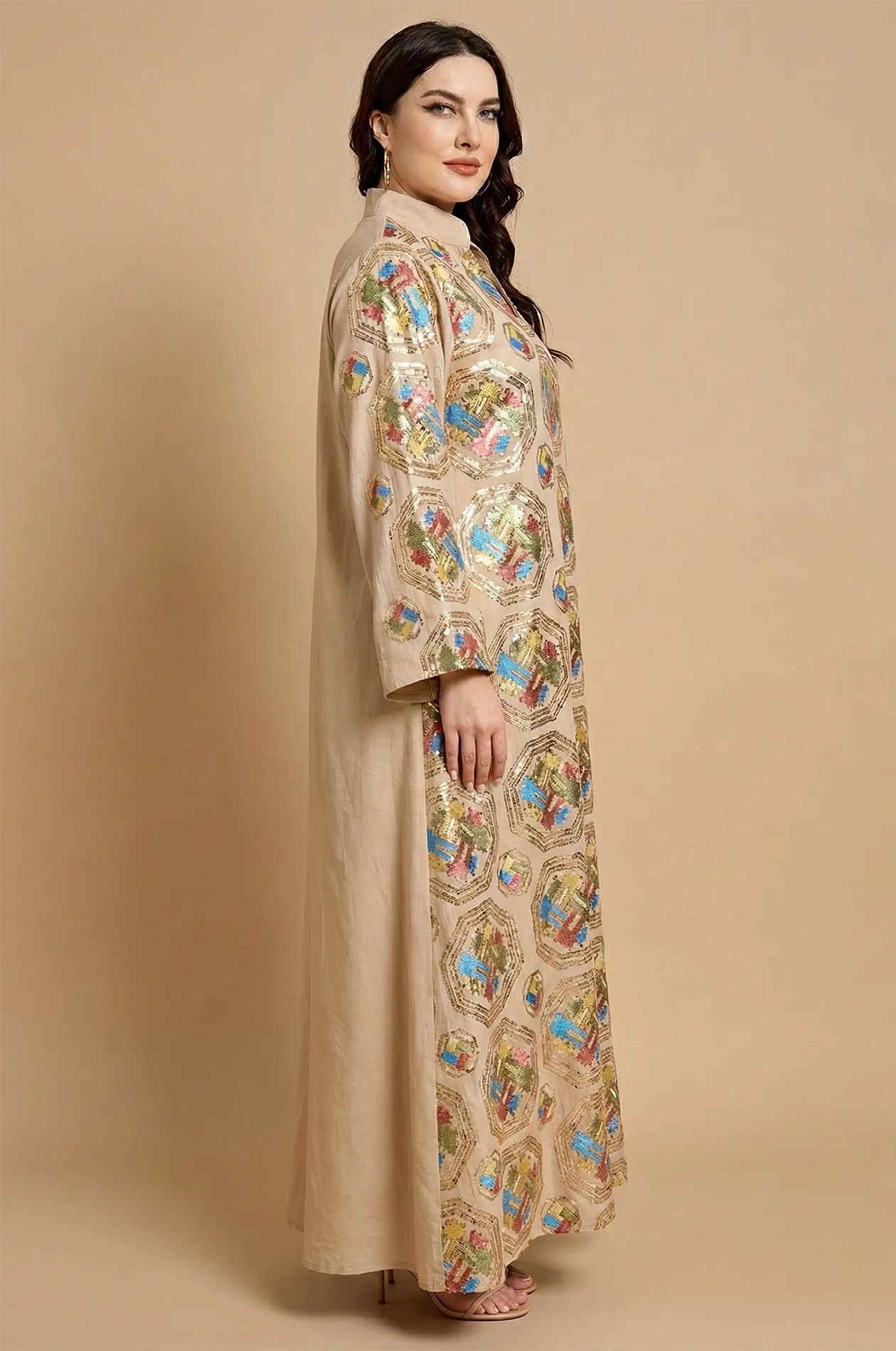 Side profile of a model wearing the Sorin beige kaftan with a mandarin collar and all-over sequin patterns.