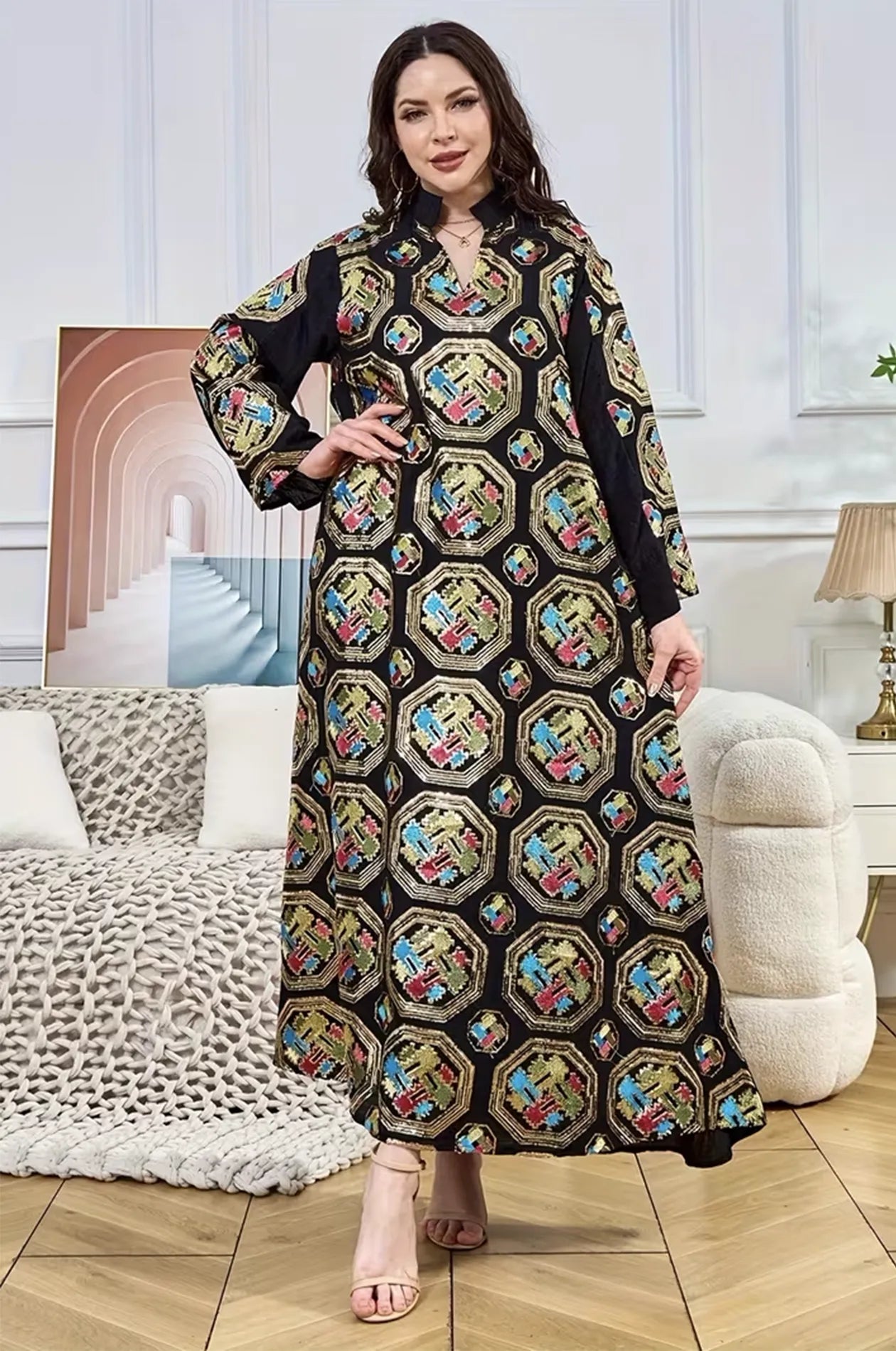 Fashion model posing in a black Sorin mandarin collar kaftan with vibrant octagonal embroidery and shimmering gold accents.