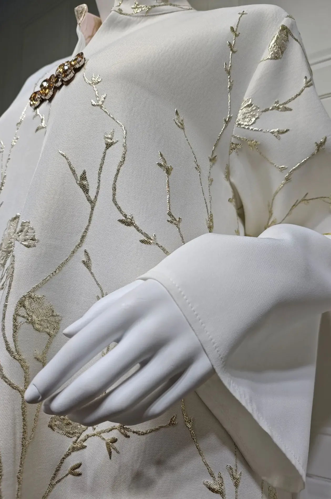 Close-up detail of the intricate silver floral embroidery and luxury crystal brooch on the Tayla Red Botanical Kaftan.