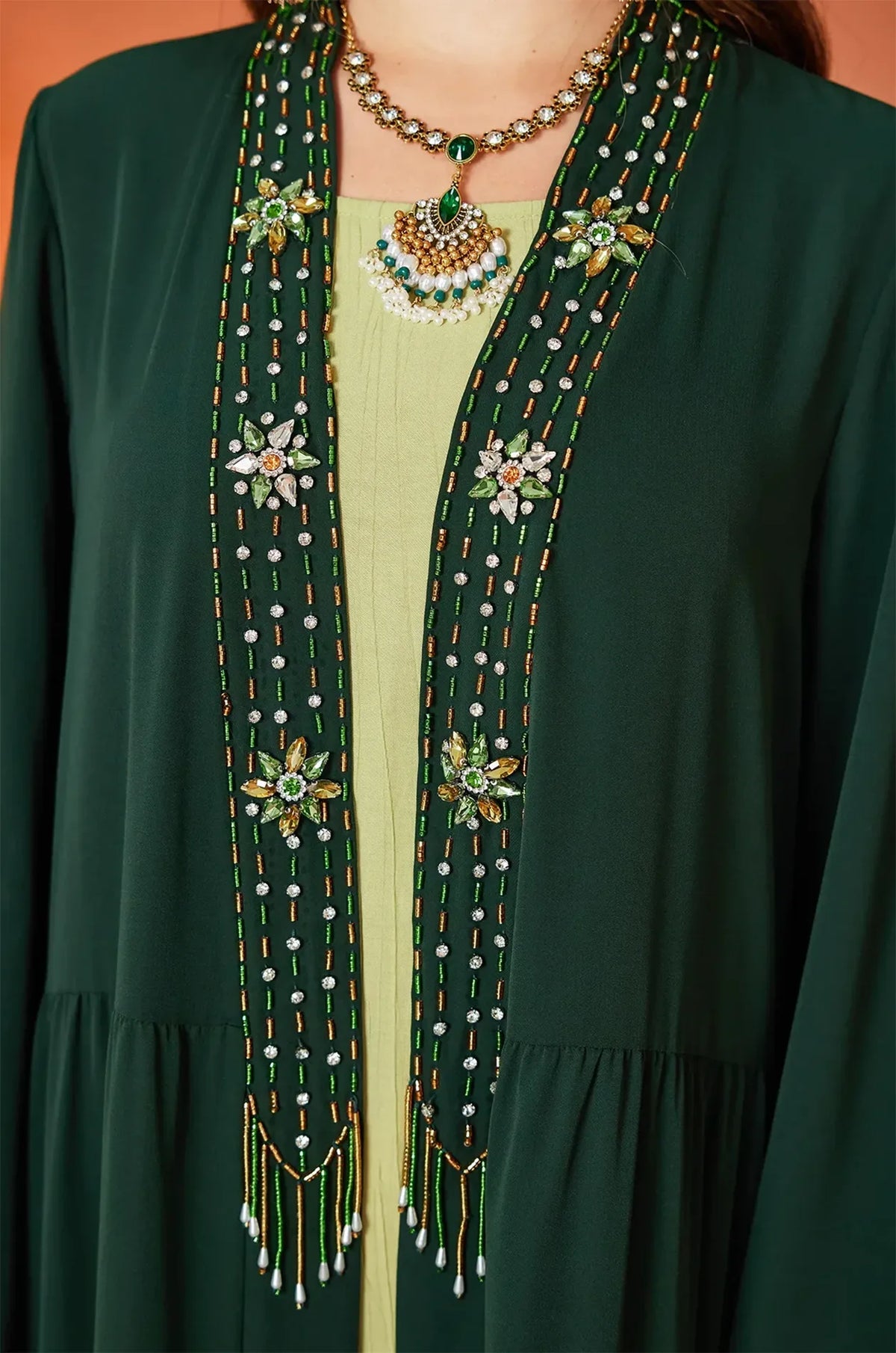 Macro detail of the green and gold beadwork and tassels on the Thais dress.