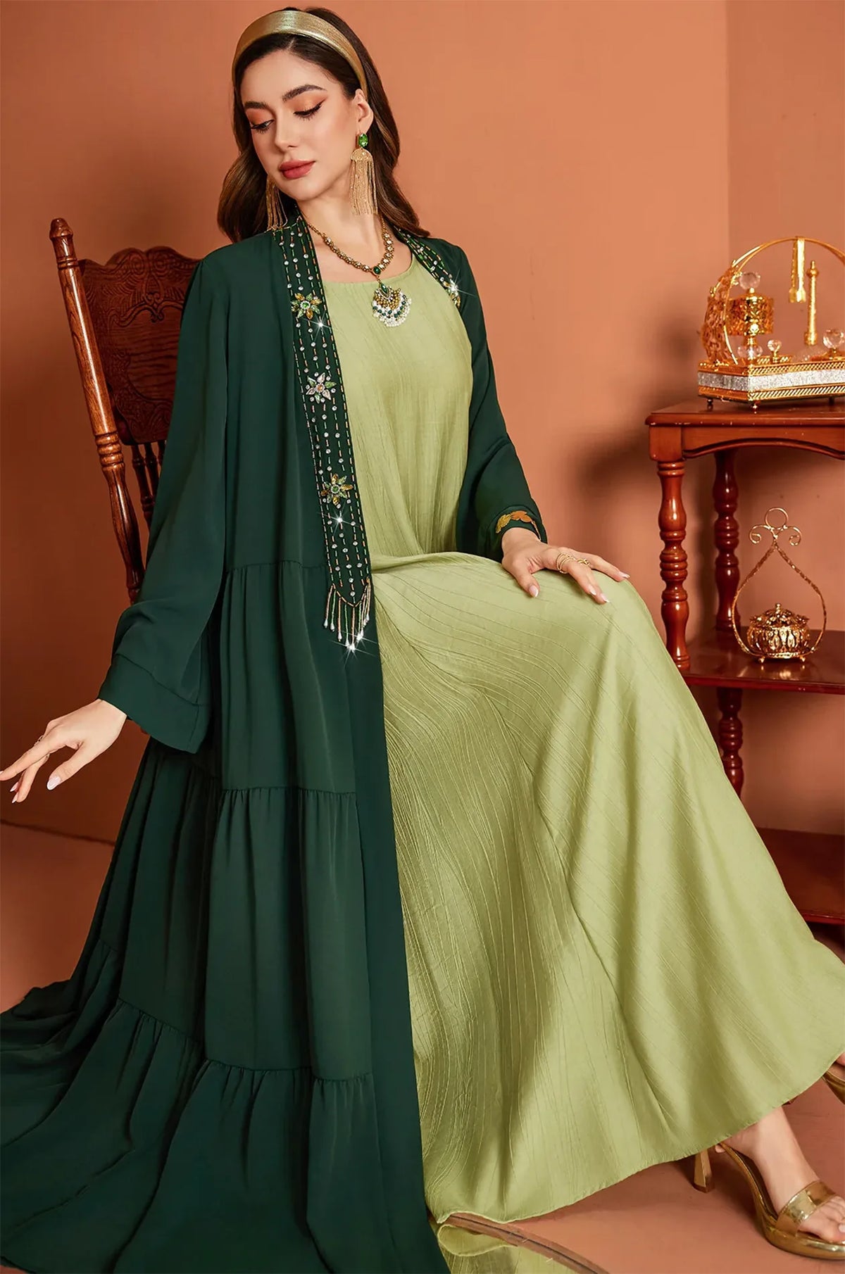 Seated view of the Thais kaftan showing fabric drape and beadwork detail.