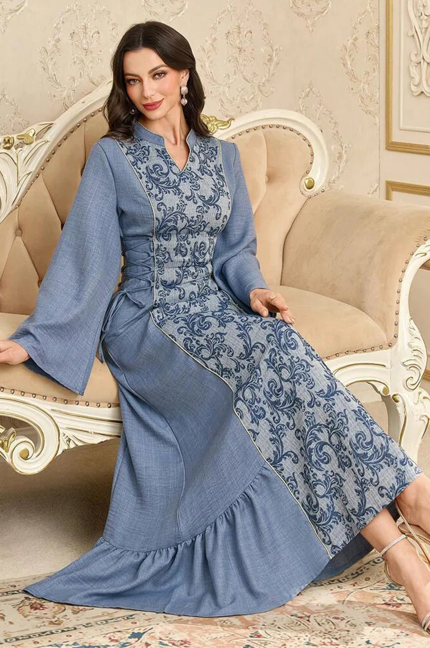 Model sitting wearing the Lumis light blue kaftan, displaying the printed panel and sleeve drape.