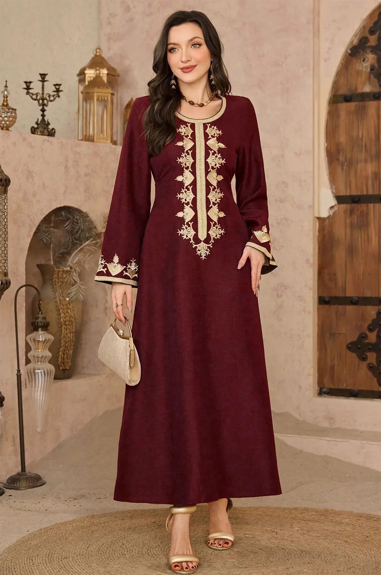 Fashion model wearing wine kaftan holding a gold clutch
