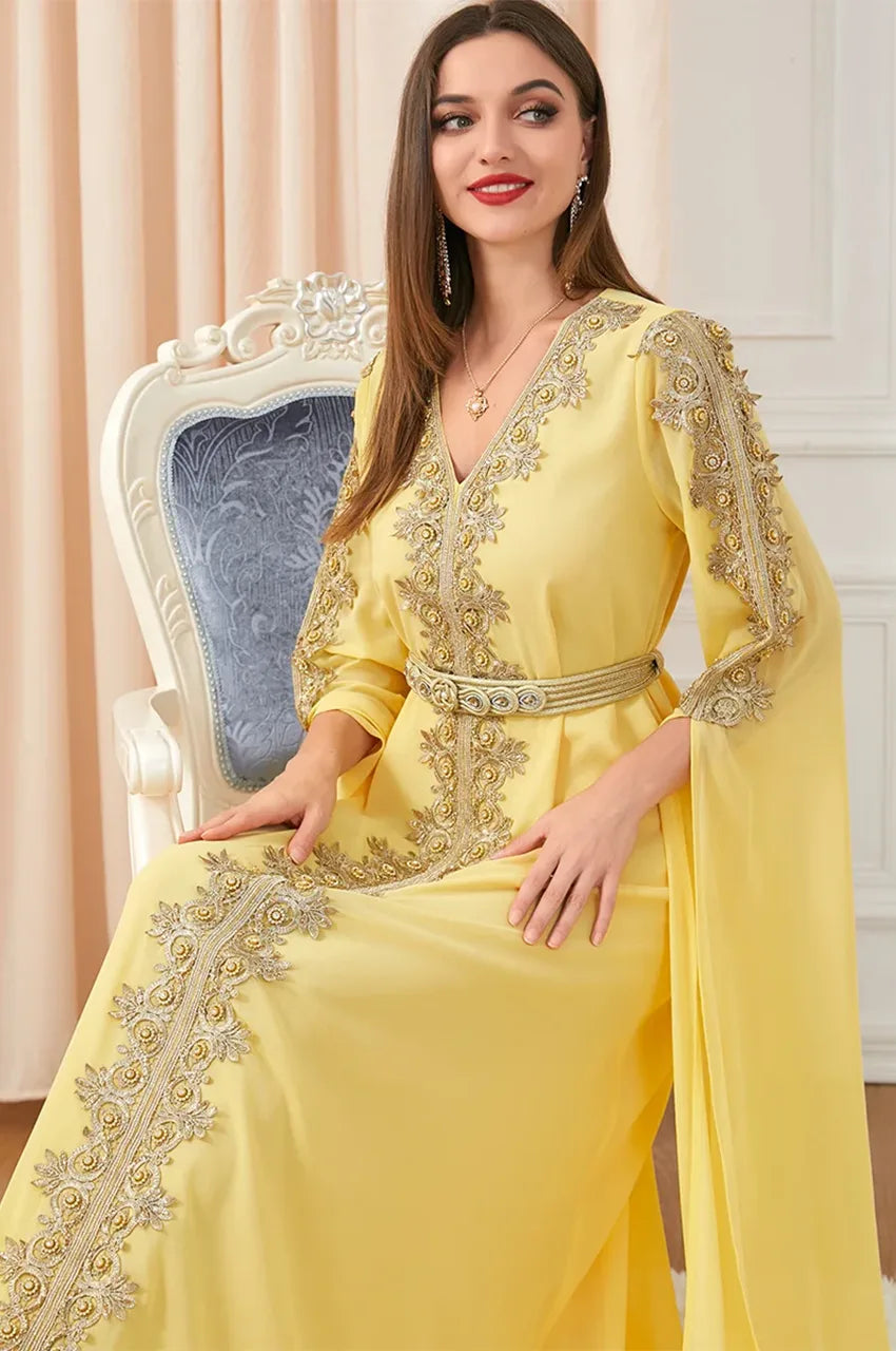 Close-up of yellow kaftan dress with ornate gold embroidery and waist belt