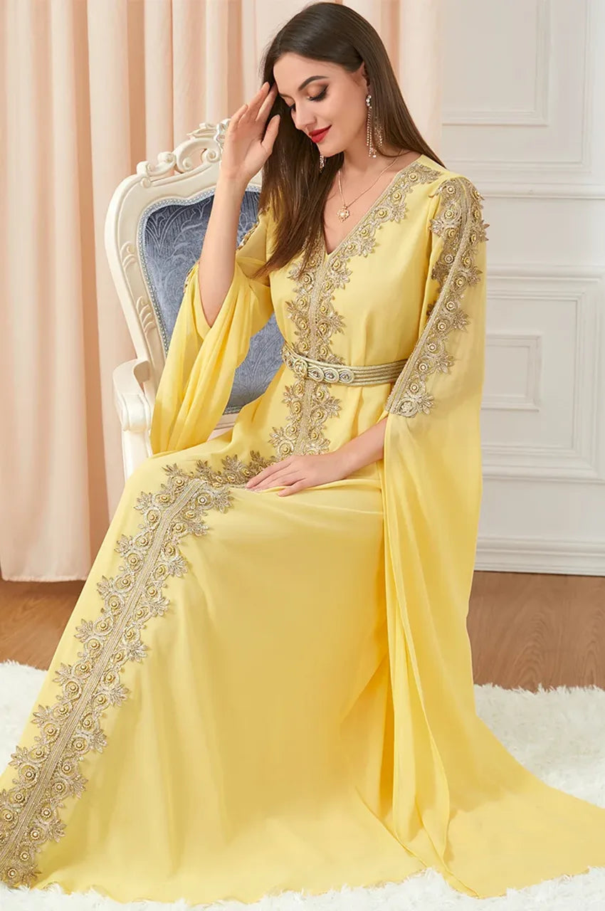 Seated model wearing elegant yellow caftan with gold embellishments