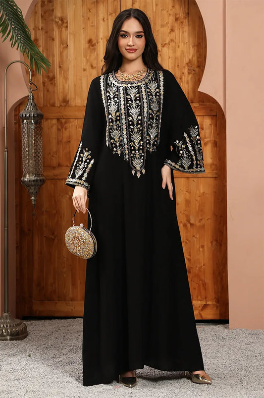 Zahia black Saudi kaftan styled with a gold clutch and opulent metallic thread-work.
