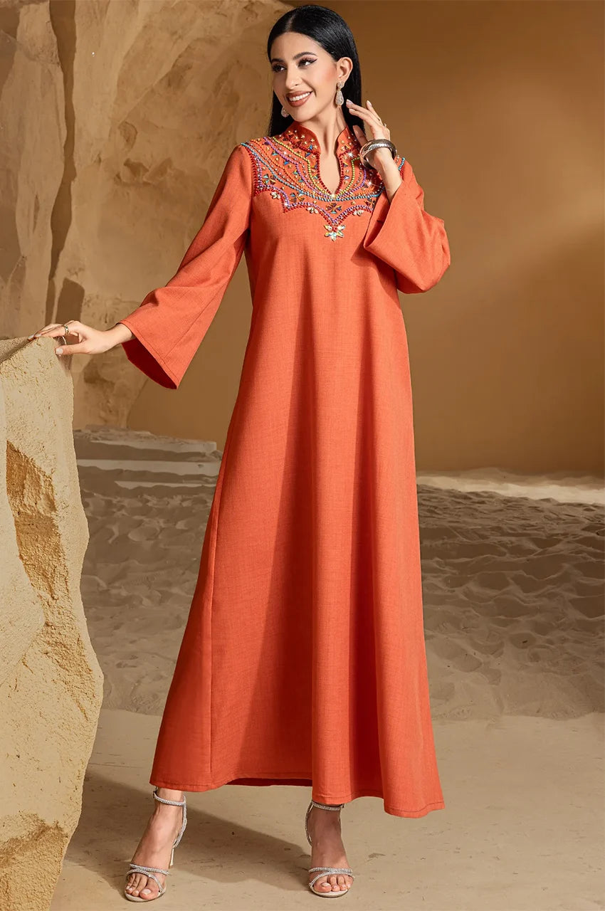 Full-length pose of Zahra orange kaftan dress in earthy background