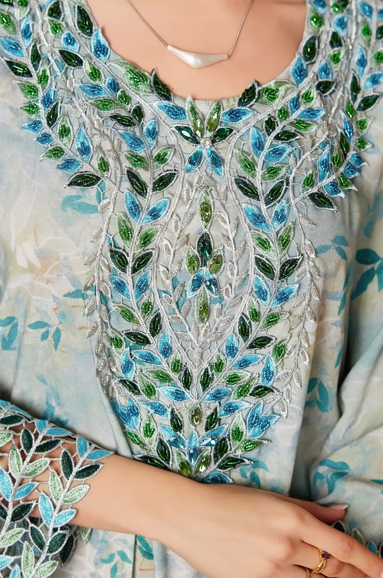 Detailed macro shot of the lace cutwork and beadwork on the kaftan sleeves.