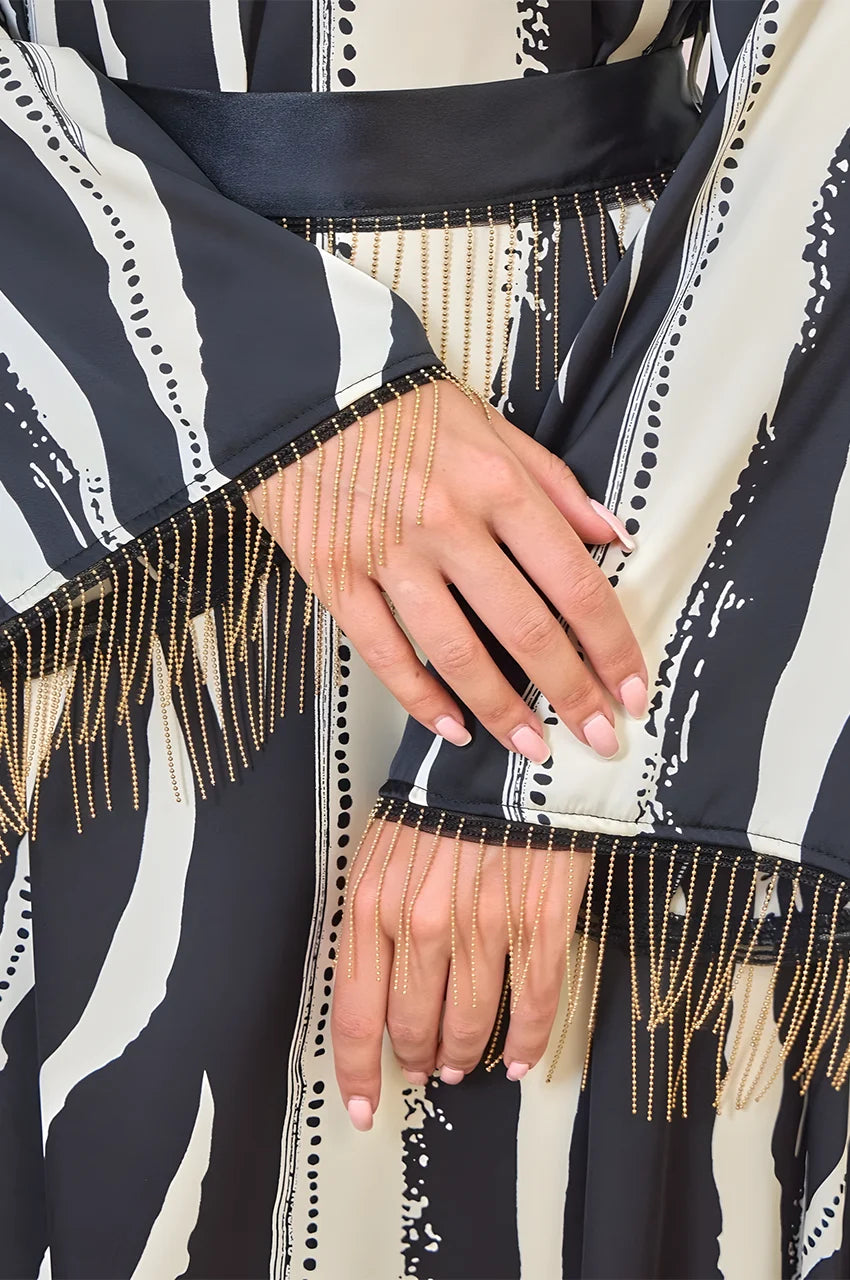 Close-up of gold chain tassels on Zayla black and white kaftan sleeves