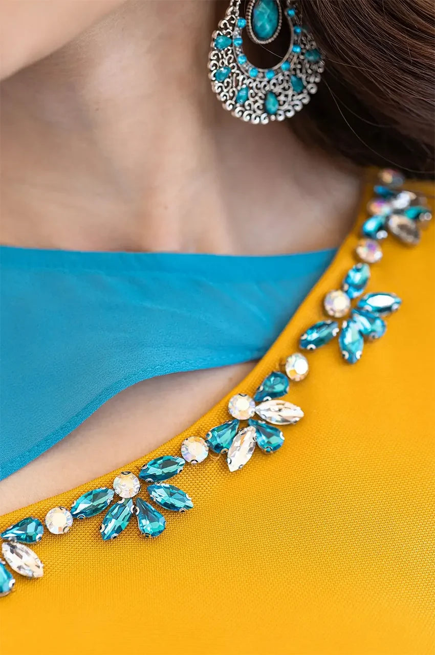 Detailed view of the crystal and teal floral rhinestone embellishments on the Zayna kaftan neckline.